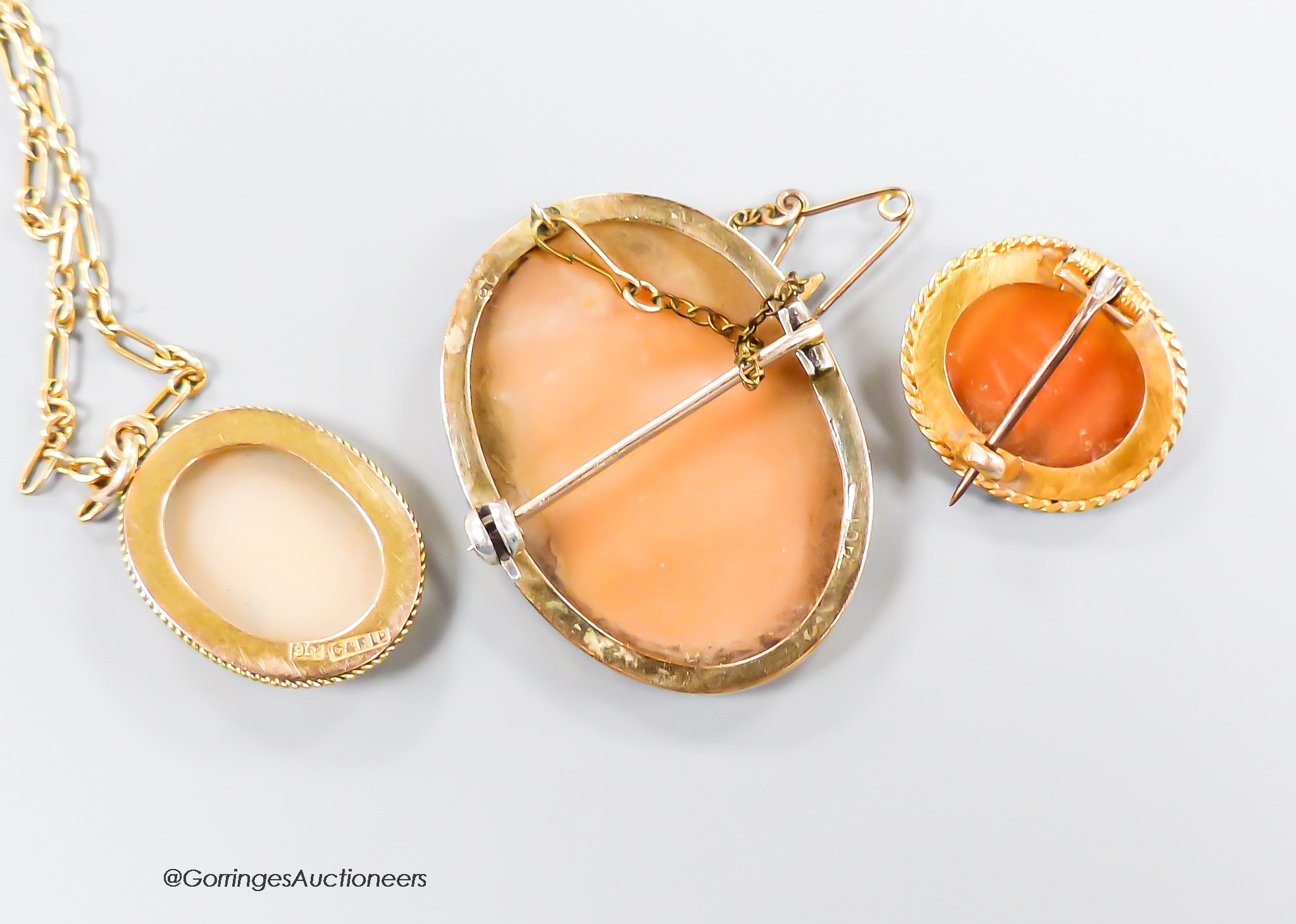 A 9ct gold mounted cameo shell pendant, 21mm, on a 9kt chain, gross 6.1 grams and two cameo shell brooches